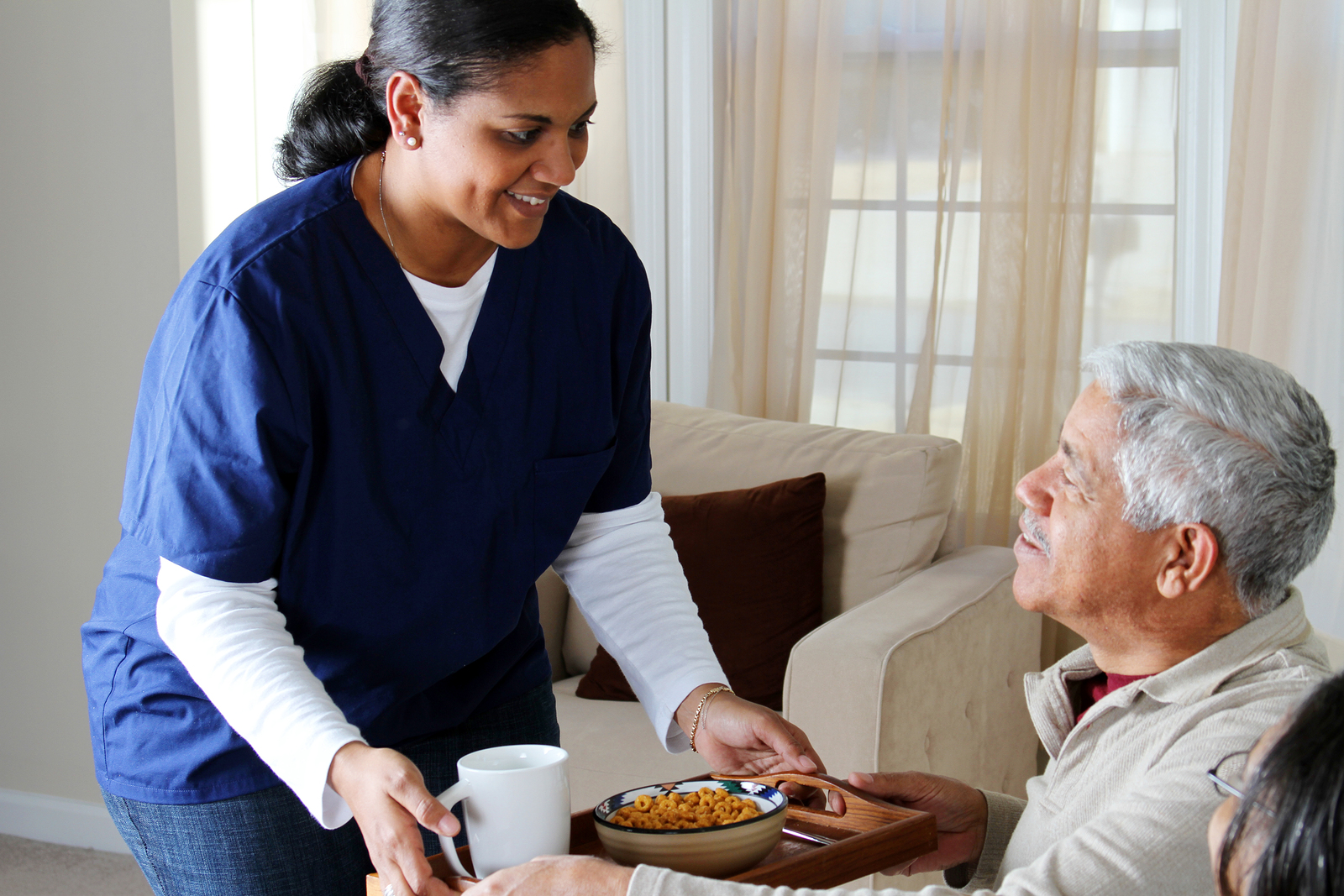 Compassionate caregiver helping a smiling senior at home in Toledo, Ohio